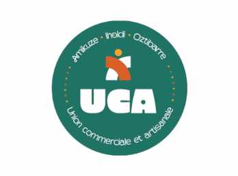 Le logo de l'Union Commerciale et Artisanale d'Amikuze est une pastille verte avec un grand UCA écrit en blanc dessus. Le logo illustre une silhouette qui se tient debout et dont le corps et dessiné par deux arcs de cercle entrelacés.